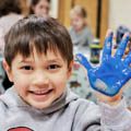 young boy with hand covered in blue paint