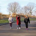 three women in winter coats walking at Schoolhouse Park