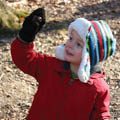 boy in winter coat and hat examining acorn