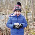 boy in winter coat and hat holding rock