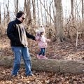 father helping daughter walk on log