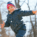 young girl running outside in her winter coat and hat