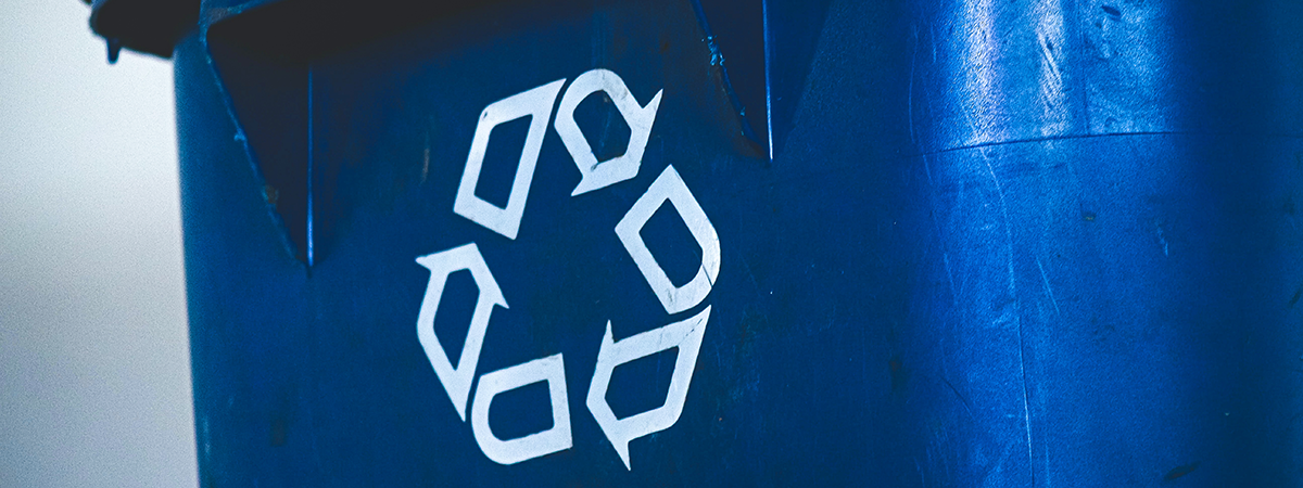 close up photo of blue recycling bin with white recycling logo