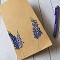Tan journal with embroidered purple flowers. A purple pen rests nearby.