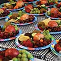 a table full of paper plates containing fruits and cheese