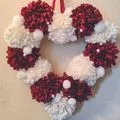 red and white heart shaped wreath made out of pom poms