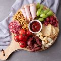 round wooden charcuterie board filled with food