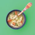 a bowl of chicken noodle soup on a green background