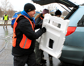 a man removing a large piece of Styrofoam from the trunk of a car