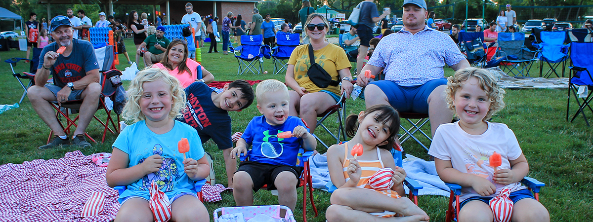 group of people sitting in lawn chairs at an outdoor movie night