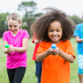 children holding colorful eggs on a spoon for a race