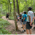 a CWPD employee giving a tour to park visitors on a cleared path in the woods