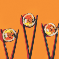 three sushi rolls laying flat with chop sticks around each roll