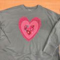 Pink hearts appliqued onto a gray sweatshirt