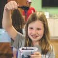 A young girl making dark purple slime