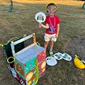 a child standing outside next to a cardboard car