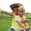 a close-up photo of a young girl and boy, both wearing yellow shirts - the girl is wearing a cowboy hat