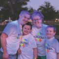 a family of 4 standing under blacklights to glow in the dark and play pickleball