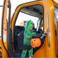 a child dressed up in a halloween costume being held up by his dad to trick or treat at a truck