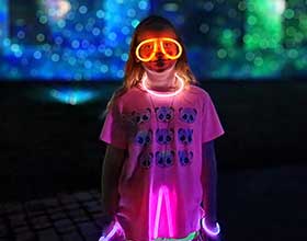 A childl standing outside wearing glow in the dark accessories