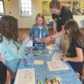 4 girls standing around a table while working on a craft project
