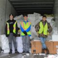 three young men standing inside of a box truck with a stack of recycled styrofoam behind them