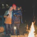 a couple standing beside a bonfire outside in the winter
