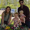 A family standing in front of a flower-filled table.