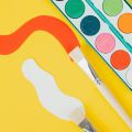 paint brushes and a paint set on a yellow background