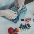 zoomed in image of hands repairing a pair of jean shorts with thread
