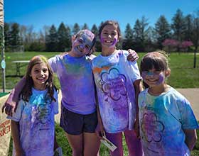 a group of four children covered in color powder