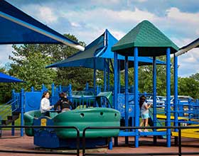 A blue and green playground with three children playing