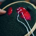 an embroidery hoop with a red mushroom being embroidered on a green background