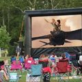 people watching a movie outdoors while sitting in lawn chairs