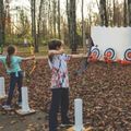 two kids shooting archery at pumpkins in the woods