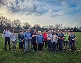 A group of adults standing in a large grassy area.